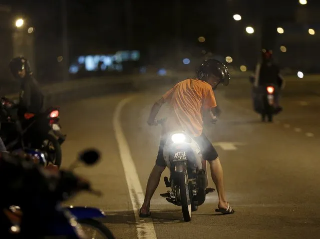 A motorcyclist revs his engine to indicate that he wants to race, on a highway in Kuala Lumpur, Malaysia, March 15, 2015. (Photo by Olivia Harris/Reuters)