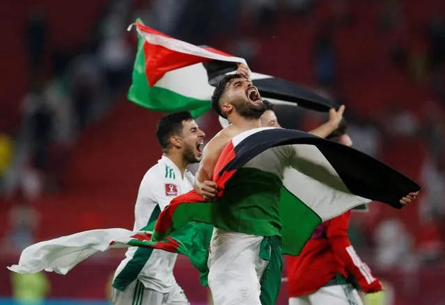 Algeria's players lift national and Palestinian flags as they celebrate their win during the FIFA Arab Cup 2021 quarter final football match between Morocco and Algeria at the Al-Thumama Stadium in the Qatari capital Doha on December 11, 2021. (Photo by Amr Abdallah Dalsh/Reuters)