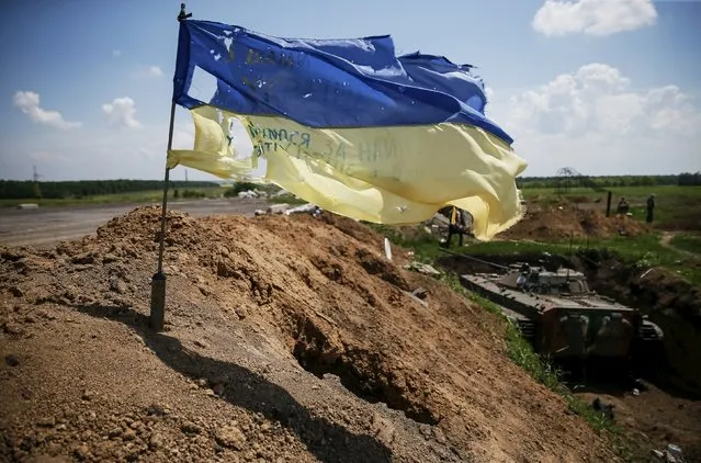 A tattered Ukrainian national flag flutters in the wind at a position held by the Ukrainian armed forces near the town of Maryinka, eastern Ukraine, June 5, 2015. Ukraine's president told his military on Thursday to prepare for a possible "full-scale invasion" by Russia all along their joint border, a day after the worst fighting with Russian-backed separatists in months.  REUTERS/Gleb Garanich