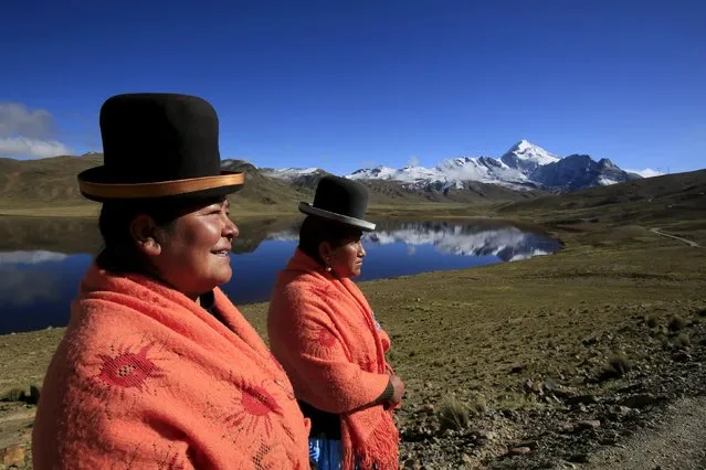 Aymara indigenous women Lidia Huayllas, 48, (L) and Dora Magueno, 50, stand near Milluni lake, with the Huayna Potosi mountain in the background, Bolivia April 6, 2016. For years, Lydia Huayllas has worked as a cook at base camps and mountain-climbing refuges on the steep, glacial slopes of Huayna Potosi, a 19,974-foot (6,088-meter) Andean peak outside of La Paz, Bolivia. But two years ago, she and 10 other Aymara indigenous women, ages 42 to 50, who also worked as porters and cooks for mountaineers, put on crampons – spikes fixed to a boot for climbing – under their wide traditional skirts and started to do their own climbing. (Photo by David Mercado/Reuters)