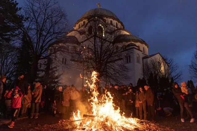 Believers burn dried oak branches, which symbolise the Yule log, on the Orthodox Christmas Eve in front of the Saint Sava temple in Belgrade, Serbia, January 6, 2022. Serbian Orthodox believers celebrate Christmas on January 7, according to the Julian calendar. (Photo by Marko Djurica/Reuters)