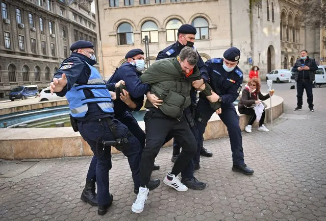 Romanian gendarmes struggle to detain a man during a protest against the newly instated restrictions due to the increasing number of COVID-19 infections in Bucharest on March 29, 2021. Around 2,000 people take part in a protest and march downtown Bucharest claiming that the restrictions are  a limitation of their civil rights. (Photo by Daniel Mihailescu/AFP Photo)