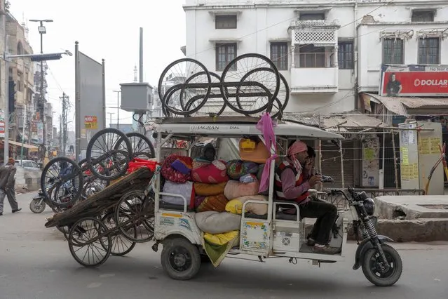 A battery-operated rickshaw carries push carts and other goods on a cold and foggy morning in Lucknow, India on January 18, 2022. (Photo by Rajesh Kumar Singh/AP Photo)