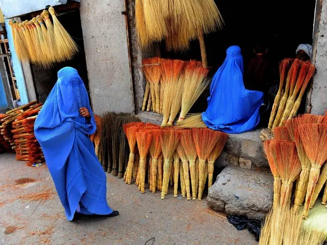 Afghan shoppers look for brooms at a roadside shop in Herat on April 9, 2014. Leading candidates in Afghanistan's presidential election voiced concern that voting was tainted by fraud after millions defied Taliban threats and turned out to choose a successor to President Hamid Karzai. World leaders praised the courage of Afghan voters, who cast their ballots in force despite bad weather and the violent campaign of intimidation, and urged patience in the long vote count. (Photo by Aref Karimi/AFP Photo)