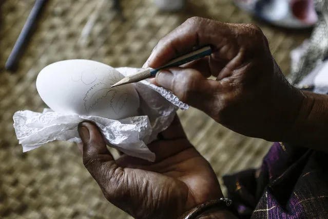 Wayan Sandra sketches a design on an eggshell at his workshop on April 14, 2014 in Sukawati, Gianyar, Bali, Indonesia. (Photo by Putu Sayoga/Getty Images)