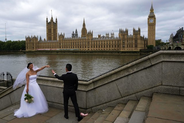 A couple take photograph outside the Houses of Parliament in London, Thursday, May 23, 2024. (Photo by Kin Cheung/AP Photo)