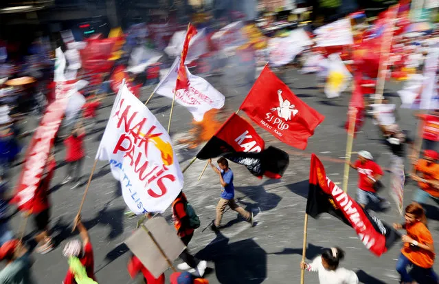 Hundreds of protesters, mostly workers, dance around the burning effigy of Philippine President Benigno Aquino III during a rally near the Presidential Palace to mark the International Labor Day Sunday, May 1, 2016 in Manila, Philippines. (Photo by Bullit Marquez/AP Photo)