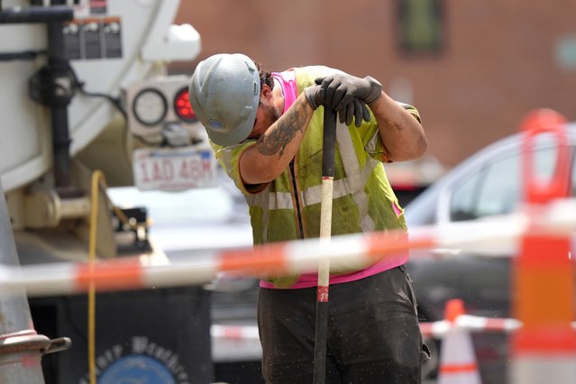 A worker wipes his face while working in temperatures above 90F (32C) at a gas line work site, Thursday, June 20, 2024, on a street in Boston. (Photo by Steven Senne/AP Photo)