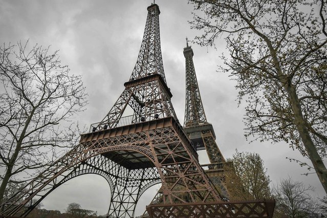 A photograph taken on April 1, 2023 shows a repliqua (L) of the Eiffel Tower, set near the original one in Paris. “Eiffela”, a replica of the famous Parisian Tower, ten times smaller than its model, has been created by Philippe Maindron and is on display until April 10, 2023. (Photo by Stephane de Sakutin/AFP Photo)