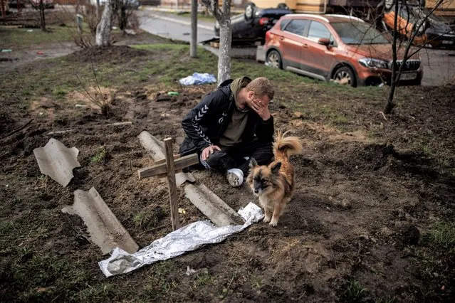 Serhii Lahovskyi, 26, mourns next to the grave of his friend Ihor Lytvynenko, who according to residents was killed by Russian soldiers, after they found him beside a building's basement, amid Russia's invasion of Ukraine, in Bucha, in Kyiv region, Ukraine, April 6, 2022. (Photo by Alkis Konstantinidis/Reuters)