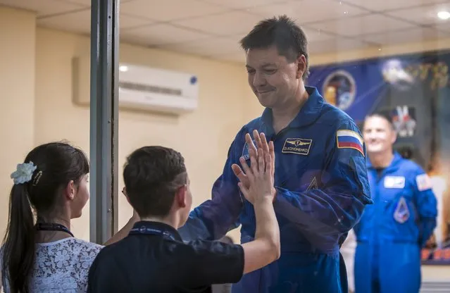 The International Space Station (ISS) crew member Oleg Kononenko of Russia interacts with his children as he stands behind a glass wall at a news conference at the Baikonur cosmodrome in Baikonur, Kazakhstan, July 21, 2015. The crew is scheduled to travel on board the Soyuz spacecraft on July 23, 2015. (Photo by Shamil Zhumatov/Reuters)