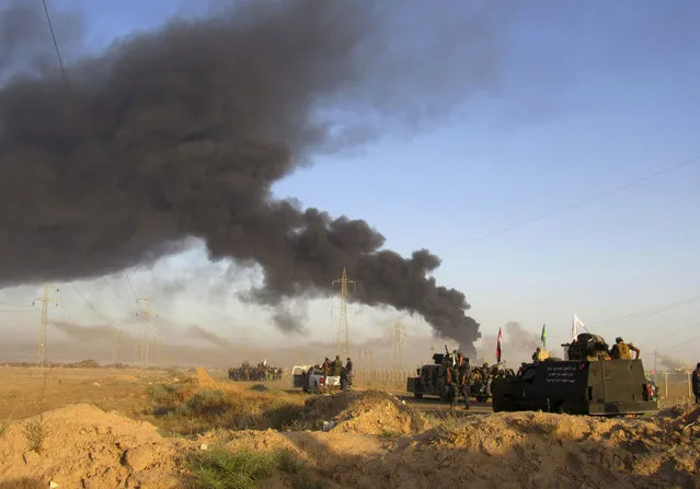 Smoke rises from Islamic State group positions after an airstrike by U.S.-led coalition warplanes in Fallujah, as Iraqi security forces and allied Shiite Popular Mobilization Forces and Sunni tribal fighters, take combat positions outside Fallujah, 40 miles (65 kilometers) west of Baghdad, Iraq, Monday, May 23, 2016. Iraqi government forces on Monday pushed Islamic State militants out of some agricultural areas outside Fallujah as they launched a military offensive to recapture the city from the extremists, officials said. (Photo by Rwa Faisal/AP Photo)
