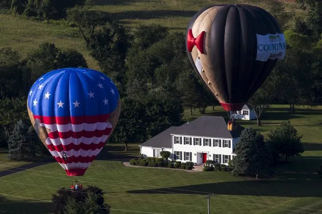 Hot air balloons land near a farmhouse as seen from a flying balloon just after sunrise on day one of the 2015 New Jersey Festival of Ballooning in Readington, New Jersey, July 24, 2015. (Photo by Mike Segar/Reuters)