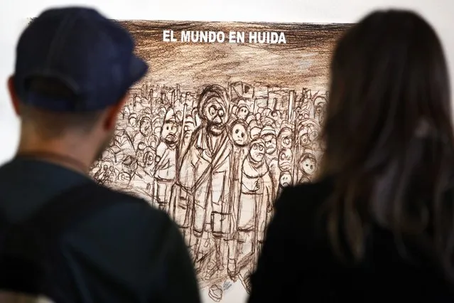 A couple regard a piece of art saying “El mundo en huida” (The world taking flight) in the exhibition “Refugiarte (Refugee-art)” at the Estacion Mapocho Cultural Center in Santiago, Chile, 27 May 2016. Several Latin American artists participated in this exhibition, presenting works of art that highlight the plight of refugees displaced by war or persecution. (Photo by Sebastian Silva/EPA)