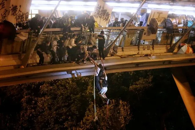 Anti-government protesters trapped inside Hong Kong Polytechnic University abseil onto a highway and escape as police besiege the campus, November 18, 2019. Dozens of protesters staged a dramatic escape by shimmying down plastic hosing from a bridge and fleeing on waiting motorbikes as the police fired projectiles. A number of them appeared subsequently to have been arrested, a Reuters witness said. (Photo by HK01 via Reuters)