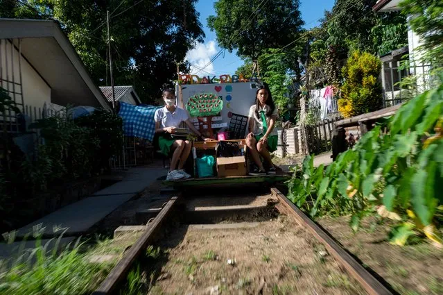 Student volunteers ride on their makeshift trolley which serves as a mobile library for children, in Tagkawayan, Quezon Province, Philippines, February 15, 2022. (Photo by Lisa Marie David/Reuters)