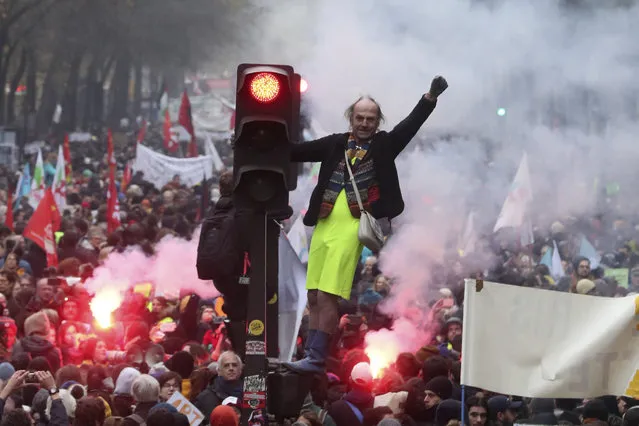 A man stands on a traffic light during a demonstration in Paris, Thursday, December 5, 2019. The Eiffel Tower shut down, France's vaunted high-speed trains stood still and several thousand protesters marched through Paris as unions launched open-ended, nationwide strikes Thursday over the government's plan to overhaul the retirement system. (Photo by Thibault Camus/AP Photo)