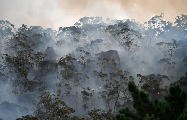 Smoke and flames from a back burn, conducted to secure residential areas from encroaching bushfires, are seen at the Spencer area in Central Coast, some 90-110 kilometres north of Sydney on December 9, 2019. Australia is experiencing a horrific start to its fire season, which scientists say began earlier and is more extreme this year due to a prolonged drought and the effects of climate change. (Photo by Saeed Khan/AFP Photo)