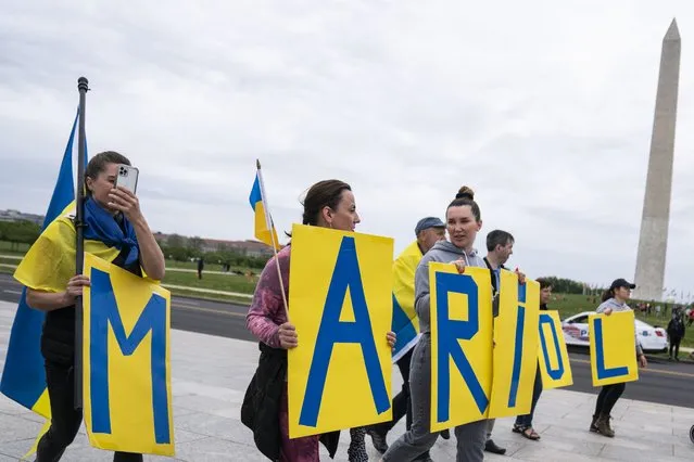 People carry signs spelling out the city Mariupol as part of a #OccupyNationalMall4Ukraine demonstration at the World War II memorial on May 1, 2022 in Washington, DC. (Photo by Sarah Silbiger/Getty Images/AFP Photo)