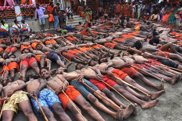 Hindu devotees lie on the ground as they wait for blessings from a priest to have good crop, prosperity and peace during the “Manda Puja” festival outside the Hindu Lord Shiva Temple in Ranchi on May 5, 2023. (Photo by Rajesh Kumar/AFP Photo)