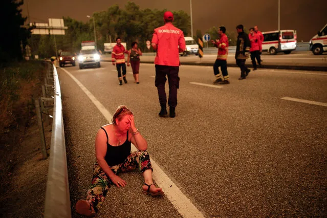 A woman sits on a street during a forest fire in Pedrogao Grande, Leiria District, Center of Portugal, 17 June 2017. About 180 firemen, 52 land vehicles and 2 planes are fighting to extinguish the fire. (Photo by Paulo Cunha/EPA)