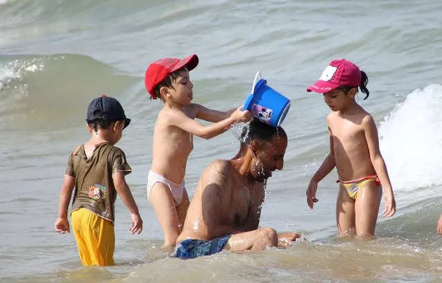 A man plays with his children in the sea on a hot day at La Goulette seaside in Tunis, Tunisia August 2, 2015. (Photo by Zoubeir Souissi/Reuters)