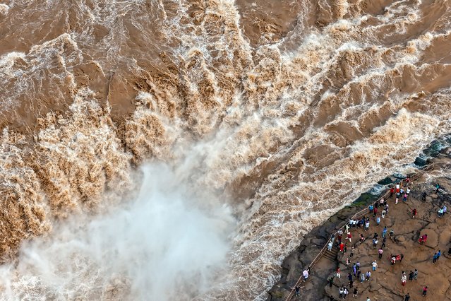 The photo taken on September 9, 2024 shows visitors watching the Hukou waterfall on the Yellow River in Linfen, in northern China's Shanxi province. (Photo by AFP Photo/China Stringer Network)