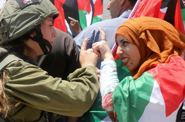 An Israeli soldier argues with a demonstrator wrapped in a Palestinian flag during a protest against Israeli settlements in Jordan Valley in the Israeli-occupied West Bank on June 6, 2022. (Photo by Raneen Sawafta/Reuters)