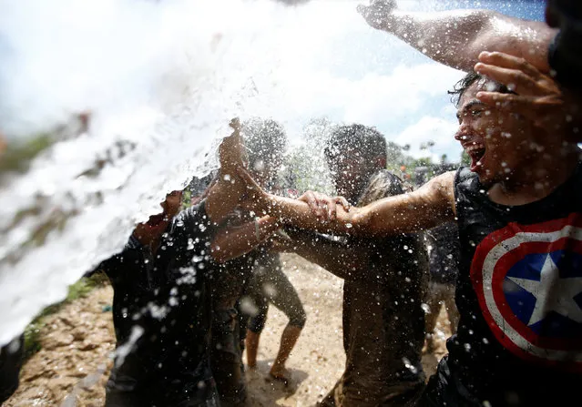 Students of Himalayan Agriculture College wash themselves after playing in the mud while celebrating Asar Pandra festival in Lalitpur, Nepal, June 29, 2016. (Photo by Navesh Chitrakar/Reuters)