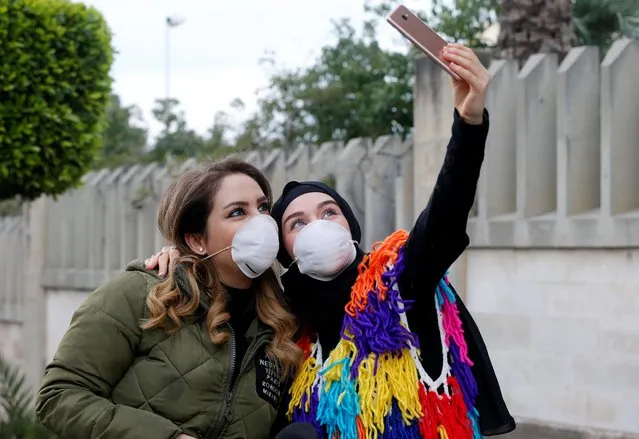 People wearing face masks take a picture with a mobile phone outside Rafik Hariri hospital, where Lebanon's first coronavirus case is being quarantined, in Beirut, Lebanon on February 21, 2020. (Photo by Mohamed Azakir/Reuters)