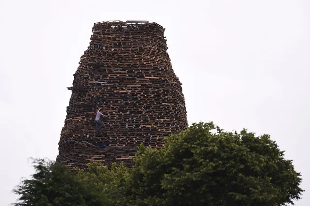 A man is seen climbing a bonfire in Ballymacash, which will be set alight at midnight on Monday, ahead of the Twelfth of July celebrations held by members of the Orange Order in Lisburn, Northern Ireland, July 10, 2016. (Photo by Clodagh Kilcoyne/Reuters)