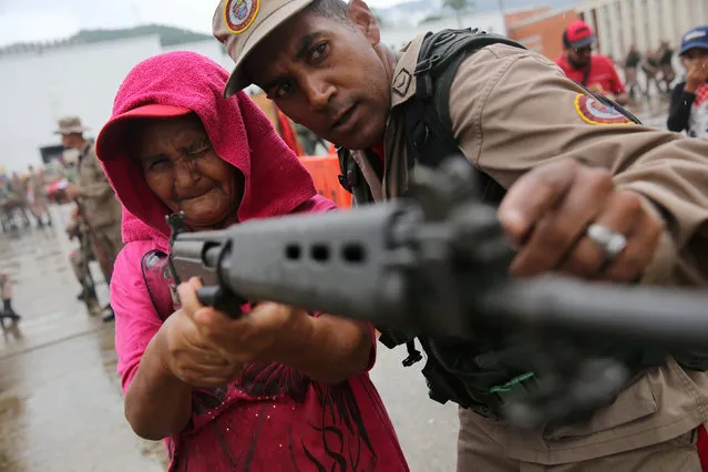 A member of the Militia of the National Bolivarian Armed Forces teaches a woman how to use a rifle during a military exercise in Caracas, Venezuela, August 26, 2017. (Photo by Andres Martinez Casares/Reuters)