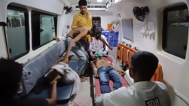 People wait to be carried into a hospital for treatment after falling sick from consuming spurious liquor in Botad, India, Tuesday, July 26, 2022. At least 21 people have died and another 30 fallen sick from drinking spurious liquor in India's western state of Gujarat, officials said Tuesday. Senior government official Mukesh Parmar said the deaths occurred in Ahmedabad and Botad districts of the state, where manufacturing, sale and consumption of liquor are prohibited. (Photo by AP Photo)