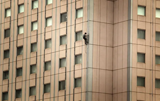 A cleaner abseils down the side of a newly renovated building in central Beijing March 5, 2012. (Photo by David Gray/Reuters)