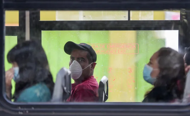 Commuters wear masks as they ride a bus, to prevent the spread of the new coronavirus in Mexico City, Tuesday, March 31, 2020. Mexico's government has broadened its shutdown of “non essential activities”, and prohibited gatherings of more than 50 people as a way to help slow down the spread of COVID-19. The one-month emergency measures will be in effect from March 30 to April 30. (Photo by Eduardo Verdugo/AP Photo)