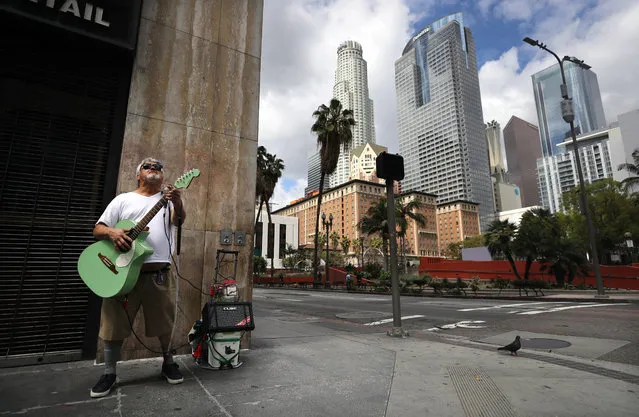 Ramon Ponce, who is blind, plays guitar and sings for extra cash around lunchtime in an unusually quiet downtown as the coronavirus pandemic continues on March 24, 2020 in Los Angeles, California. California Governor Gavin Newsom issued a ‘stay at home’ order for California’s 40 million residents in order to slow the spread of COVID-19. (Photo by Mario Tama/Getty Images)