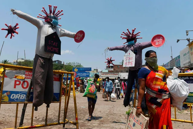 A women wearing a facemask walks past Covid-19 awareness scarecrows placed by Chennai municipality at a market during a government-imposed nationwide lockdown as a preventive measure against the COVID-19 coronavirus, in Chennai on April 11, 2020. (Photo by Arun Sankar/AFP Photo)