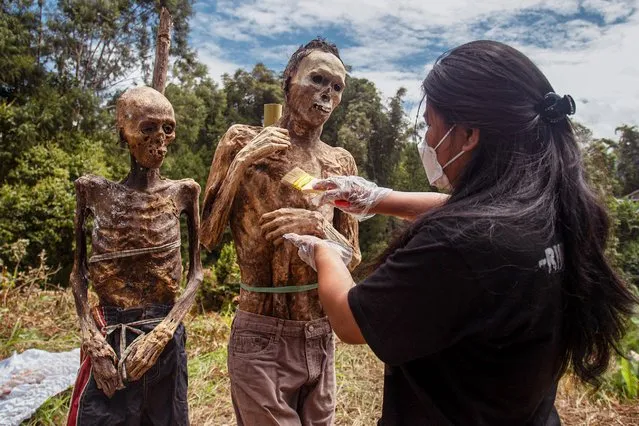 A family member of the Toraja ethnic group prepares the bodies of exhumed relatives from a community burial site to be cleaned and dressed in a series of traditional ceremonies honouring the dead known as Manene at Torea village, in North Toraja, Indonesia's South Sulawesi on August 17, 2022. (Photo by Andri Saputra/AFP Photo)