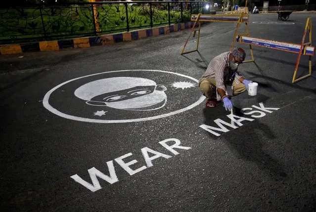 A man draws an awareness message on a road about wearing mask amid concerns about the spreading of coronavirus disease (COVID-19) in Ahmedabad, India, April 21, 2020. (Photo by Amit Dave/Reuters)