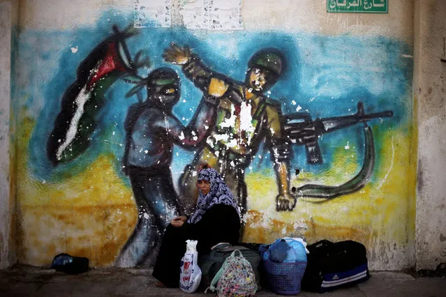 A woman sits in front of a mural as she waits for a travel permit to cross into Egypt through the Rafah border crossing after it was opened by Egyptian authorities on Wednesday for five days, in the southern Gaza Strip June 30, 2016. (Photo by Ibraheem Abu Mustafa/Reuters)
