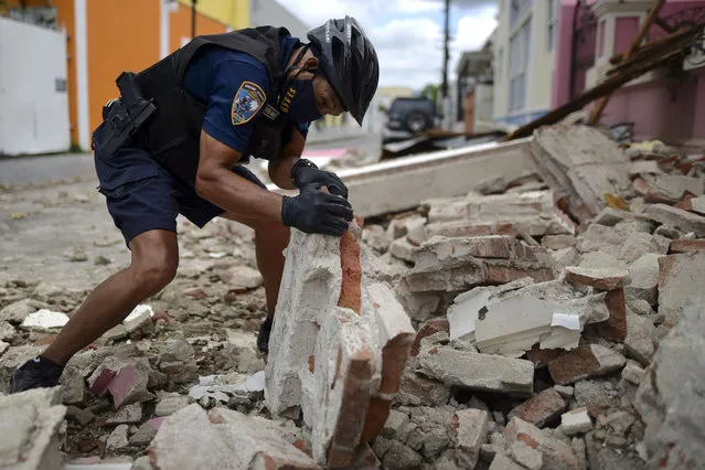 Un policía con una máscara protectora por el coronavirus, retira escombros dejados por un sismo de magnitud 5,4 en Ponce, Puerto Rico, el sábado, 2 de mayo del 2020. No hubo informes inmediatos de víctimas. (Photo by Carlos Giusti/AP Foto)