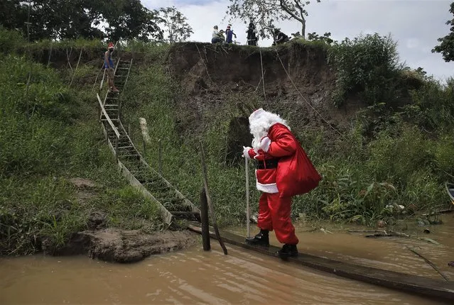 A man dressed as Santa Claus visits a community along the jungle shoreline to give out presents to children in the Amazon basin, near Careiro da Varzea, Amazonas state, Brazil, Saturday, December 18, 2021. (Photo by Edmar Barros/AP Photo)