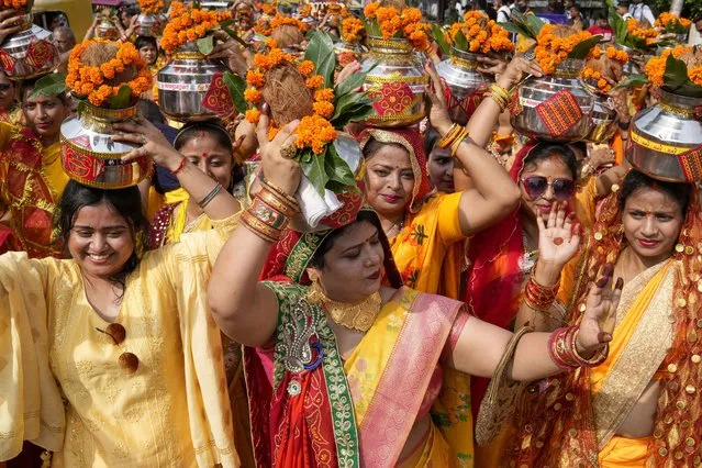 Hindu women carry water from River Ganges on their heads and walk in a procession as they perform a ritual in Prayagraj, northern Uttar Pradesh state, India, Monday, October 10, 2022. (Photo by Rajesh Kumar Singh/AP Photo)