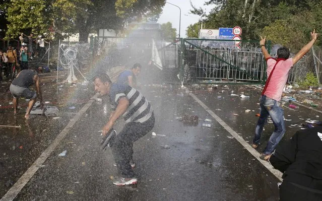 Migrants react on the Serbian side of the border as Hungarian riot police fires tear gas and water cannon near Roszke, Hungary September 16, 2015. (Photo by Marko Djurica/Reuters)