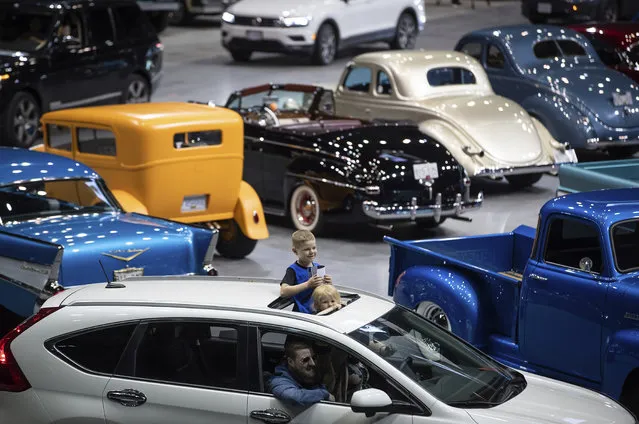 Children stand through a sunroof while attending a drive-thru classic and custom car show on the arena floor at Pacific Coliseum, in Vancouver, British Columbia, Sunday, June 21, 2020. The car show was hosted by the Pacific National Exhibition as part of a drive-thru barbecue event in support of food vendors unable to sell at the fair this year due to the cancellation of the annual event because of the coronavirus. (Photo by Darryl Dyck/The Canadian Press via AP Photo)