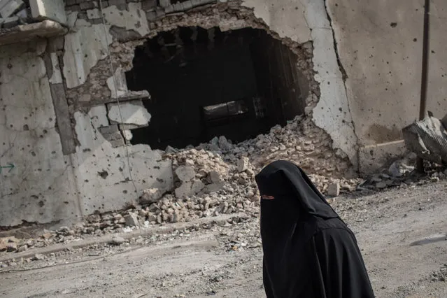 A woman walks past a destroyed building in an outer neighborhood of the Old City in West Mosul on November 6, 2017 in Mosul, Iraq. (Photo by Chris McGrath/Getty Images)