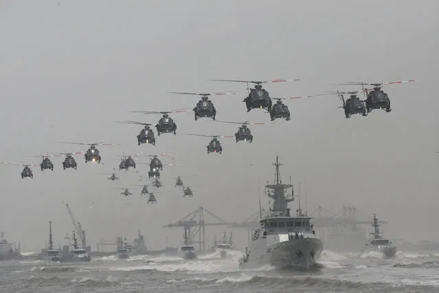 Indonesian Air Force helicopters fly in formation over the fleet of military ships in a show of force during a ceremony commemorating the 69th anniversary of Indonesian Armed Forces in Surabaya, East Java, Indonesia, Tuesday,  October 7, 2014. (Photo by AP Photo/Trisnadi)