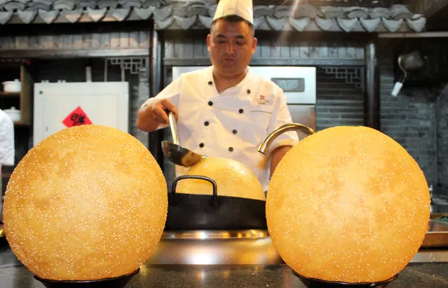 A chef makes huge sesame seed balls at a food store in Pingjiang Road on September 22, 2015 in Suzhou, Jiangsu Province of China. The diameter of sesame seed ball is in 30 centimeters which attracts citizens and visitors. (Photo by ChinaFotoPress/ChinaFotoPress via Getty Images)