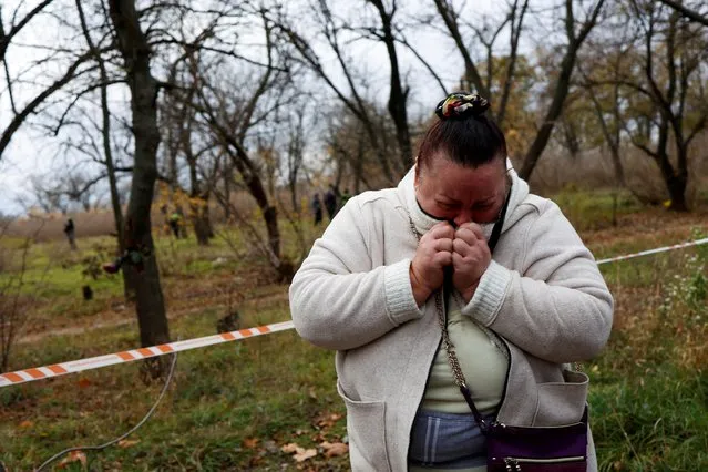 A woman reacts as Ukrainian police forensic experts search for evidence at a park where fighting took place between Ukrainian territorial forces and Russian forces at beginning of the war, in Kherson, Ukraine on November 16, 2022. (Photo by Murad Sezer/Reuters)