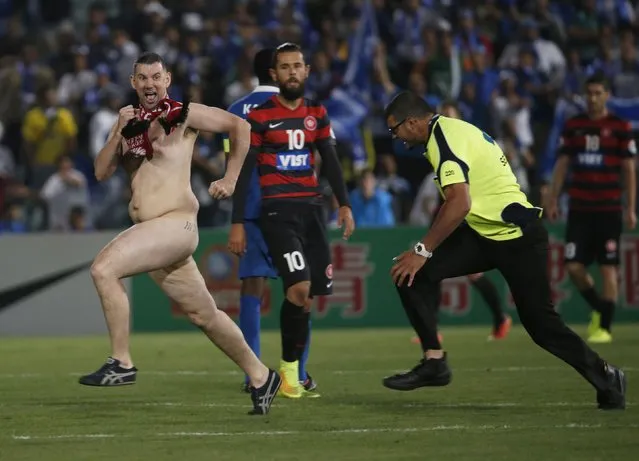 A streaker runs across the pitch as a security guard prepares to tackle him during the Asian Champions League final first-leg soccer match between Australia's Western Sydney Wanderers and Saudi Arabia's Al Hilal at Parramatta Stadium in Sydney October 25, 2014. (Photo by Jason Reed/Reuters)